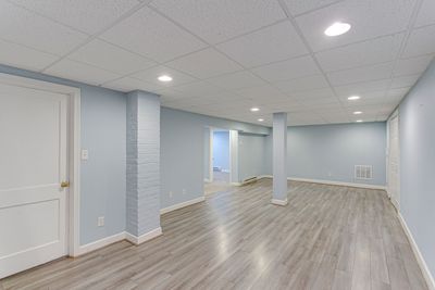 An empty basement with hardwood floors and blue walls.